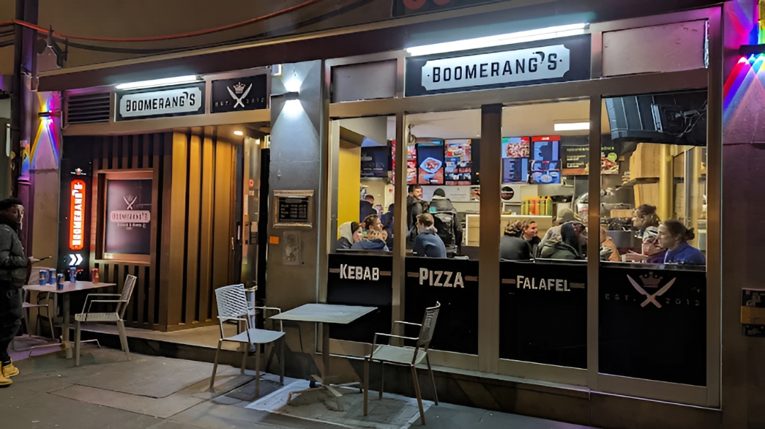 Boomerang's Ladenlokal bei Nacht im Sternengässchen, Bern — beleuchtete Fenster mit Gästen drinnen